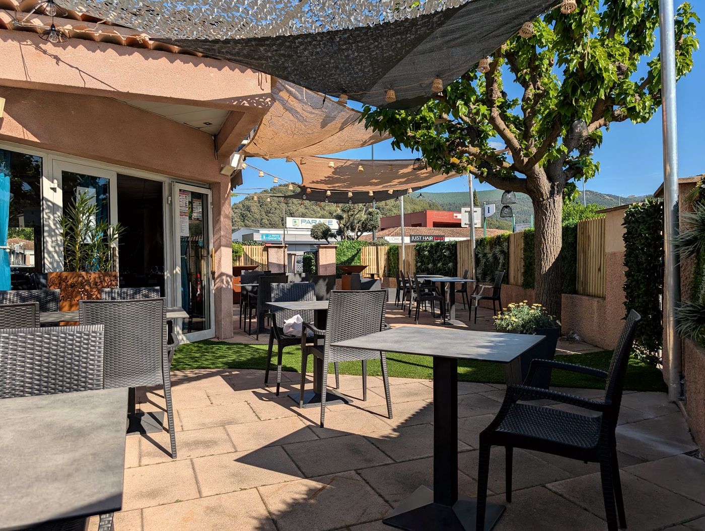 La terrasse ombragée, tables dressées sous les voiles